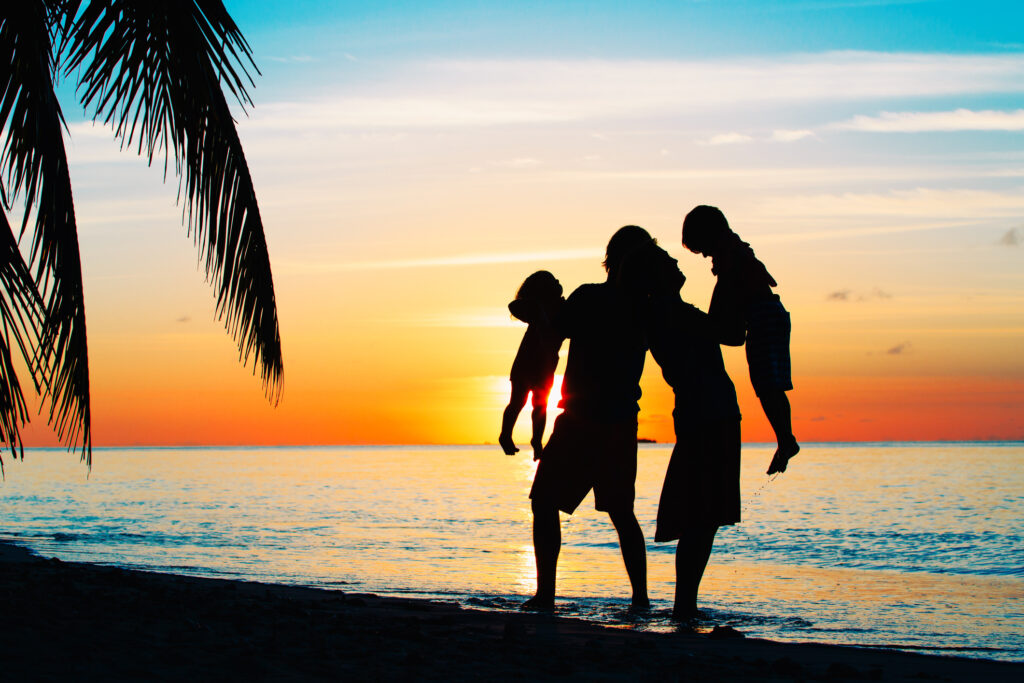 happy family with two kids play on sunset tropical beach