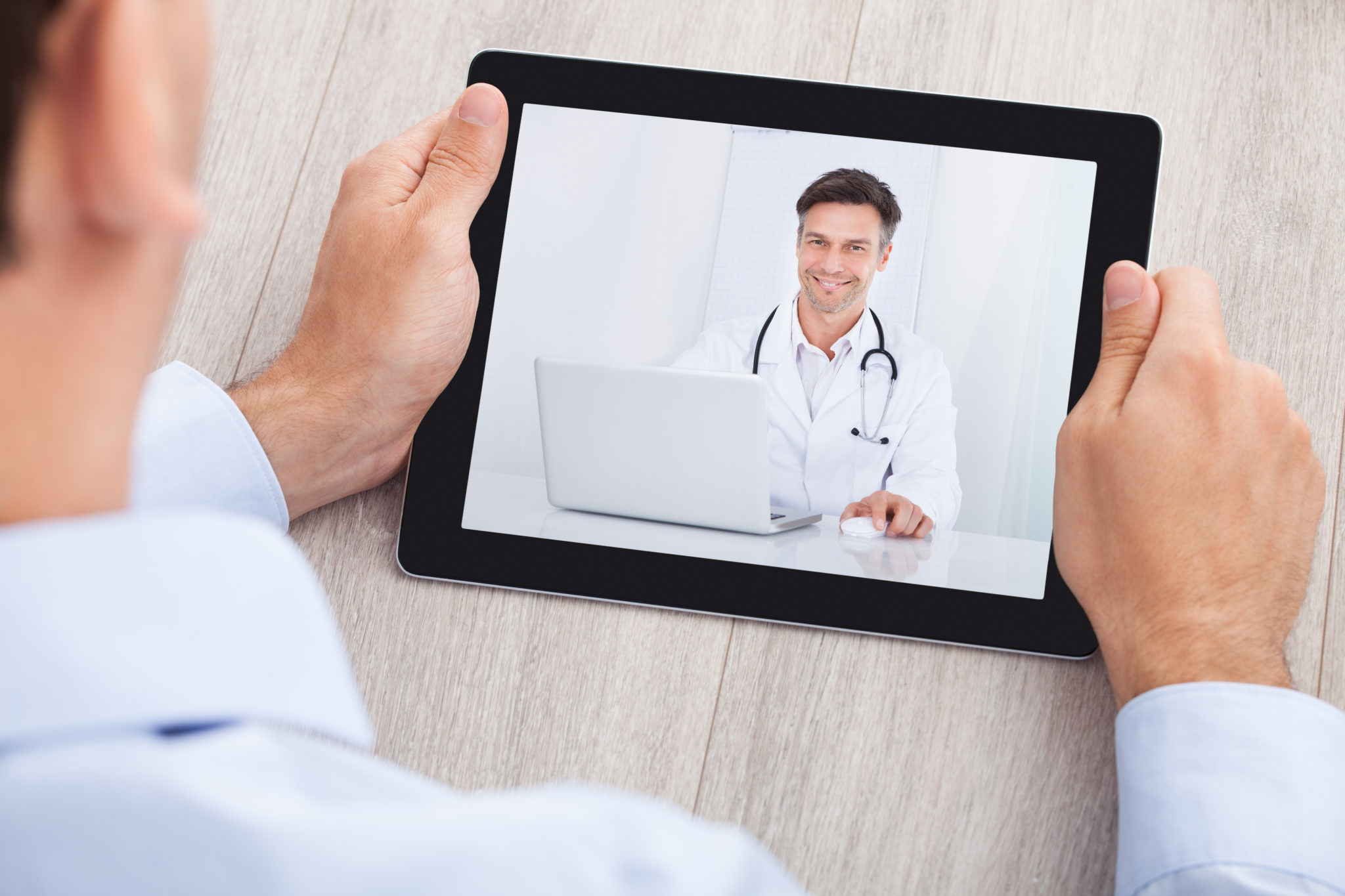 Cropped image of businessman video conferencing with doctor on digital tablet at desk in office