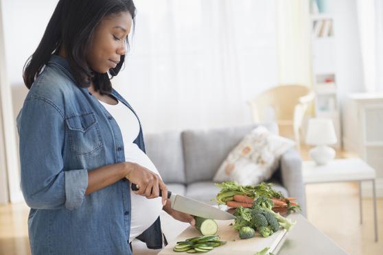 Pregnant woman chopping vegetables 
