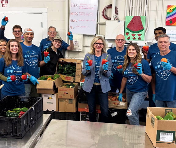 A group of people posting with fresh vegetables.