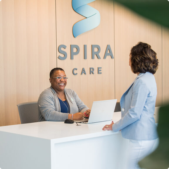 Receptionist smiling at the front desk of a Spira Care facility