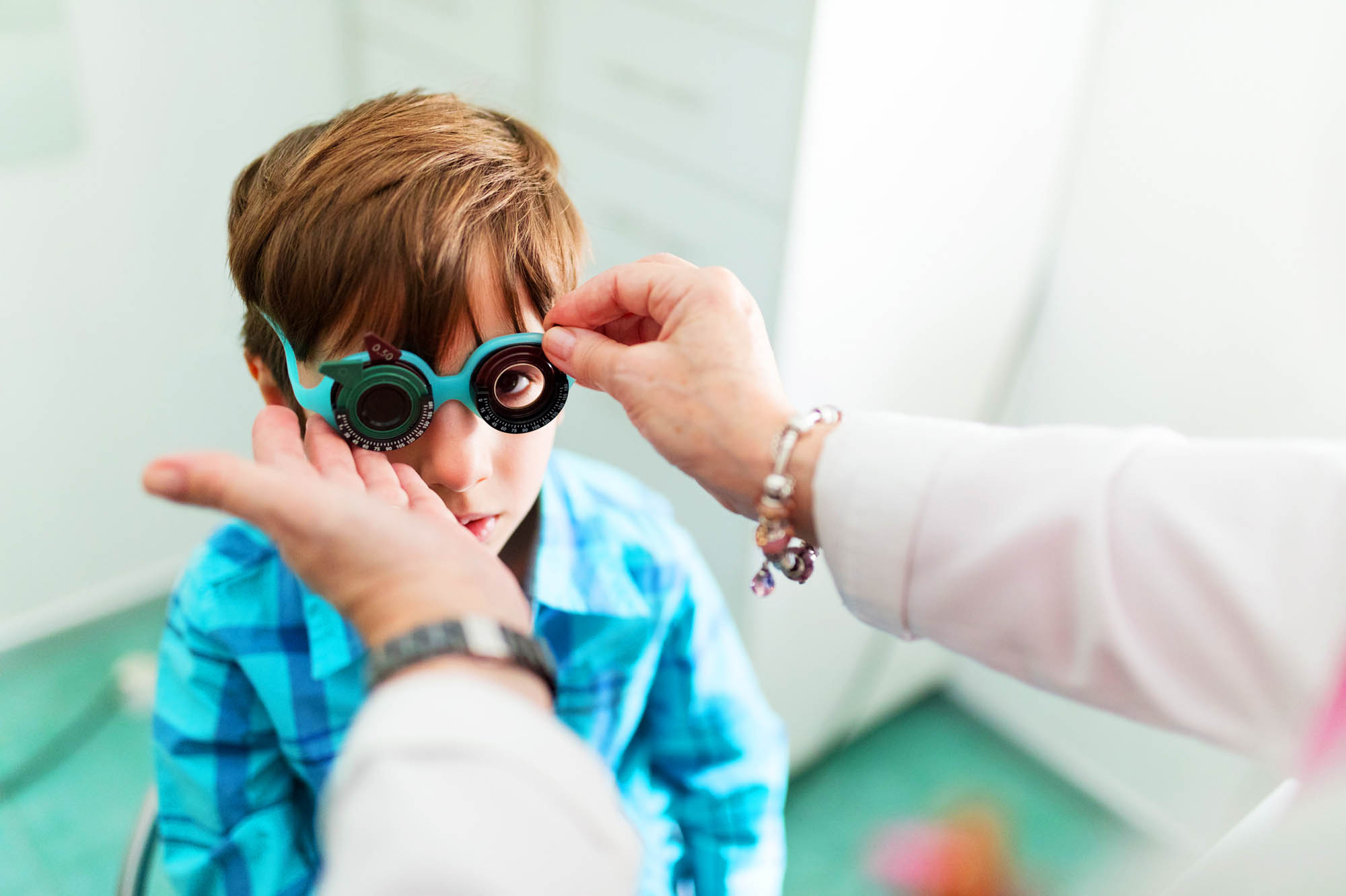 Little boy trying on new glasses at the eye doctor